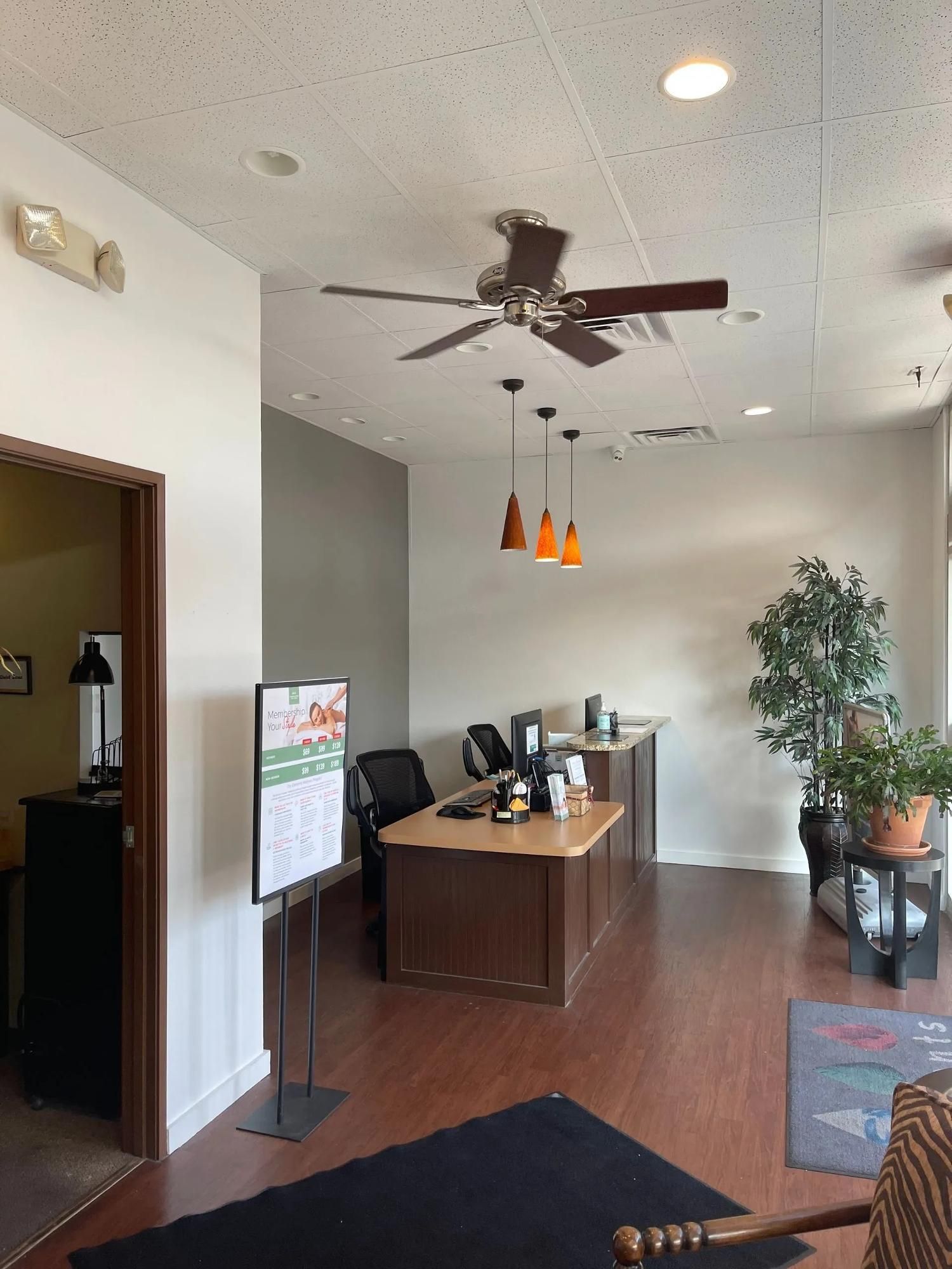 Office lobby with desk, ceiling fan, potted plants, and hardwood floors
