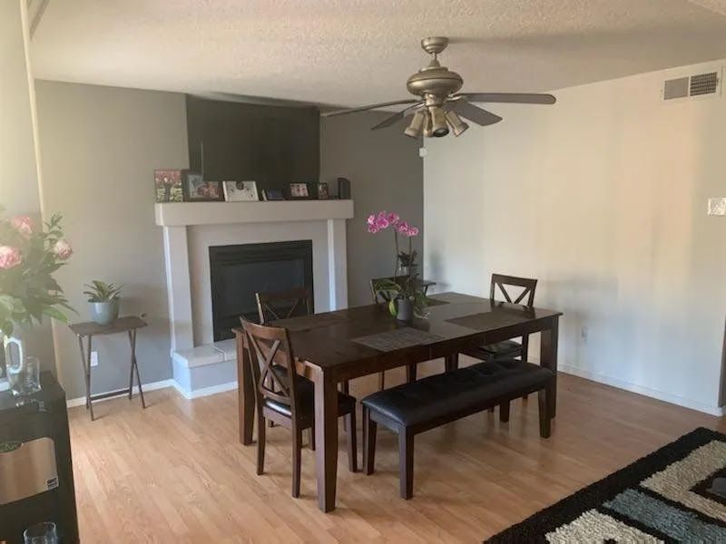 Dining room with dark wood table and chairs, fireplace, ceiling fan, and orchid plant on the table