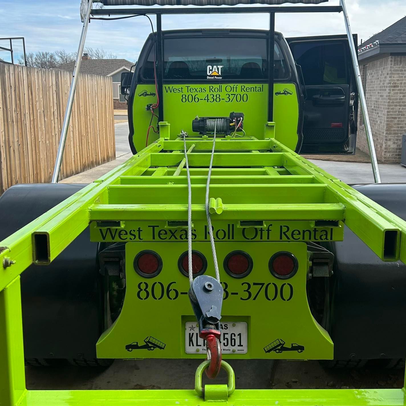 A green truck with a trailer attached to it that says west texas roll off rental