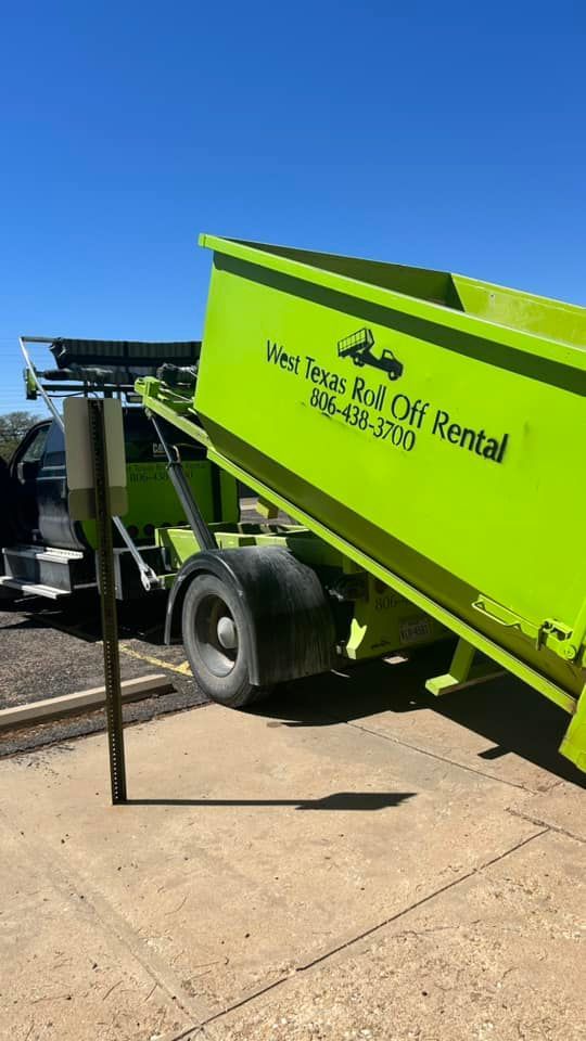 A dumpster is sitting on the side of the road next to a truck.