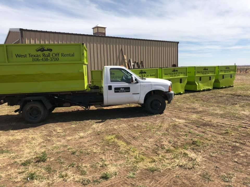 A dump truck is parked in a field next to a building.