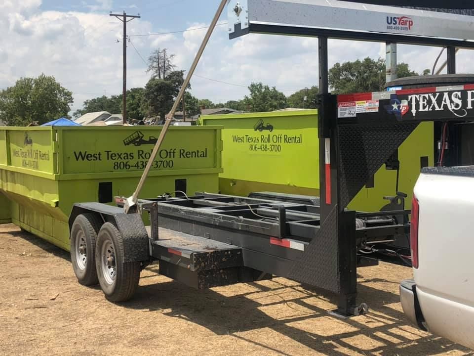 A dumpster trailer is parked next to a truck.