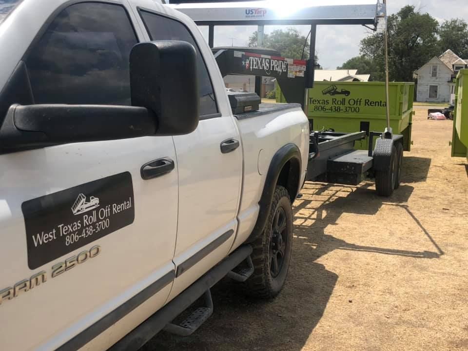 A white truck is parked next to a green trailer.