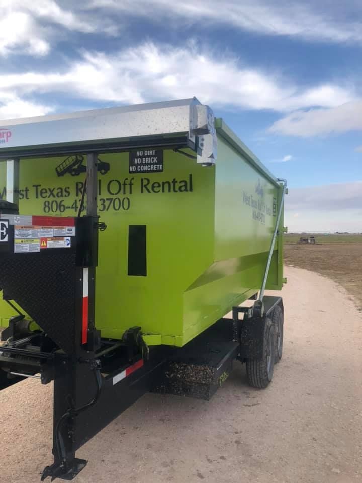 A green dumpster for texas roll off rental is parked on a dirt road