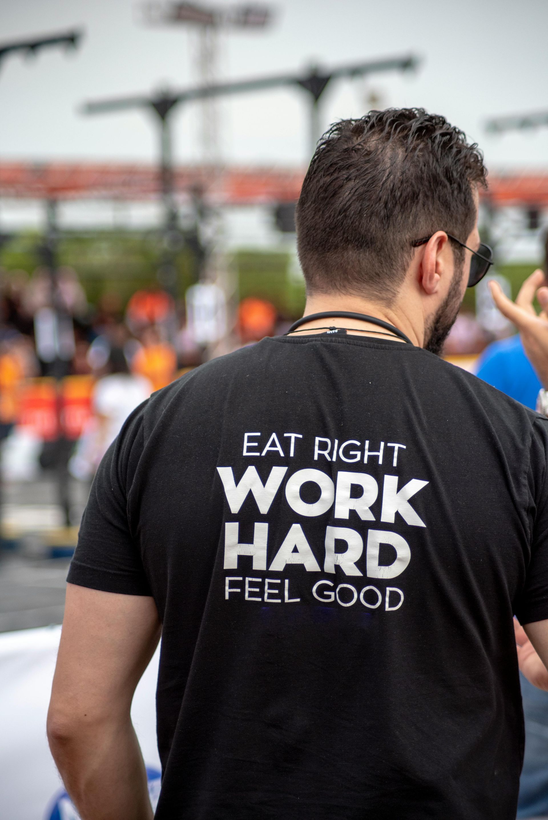 A man is wearing a black t-shirt that says `` eat right work hard feel good ''.