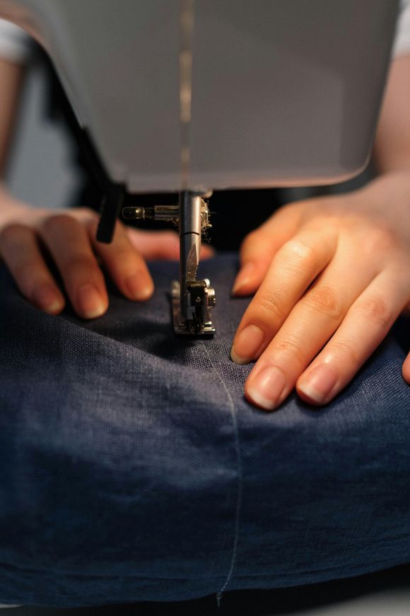 A person is using a sewing machine to sew a pair of jeans.