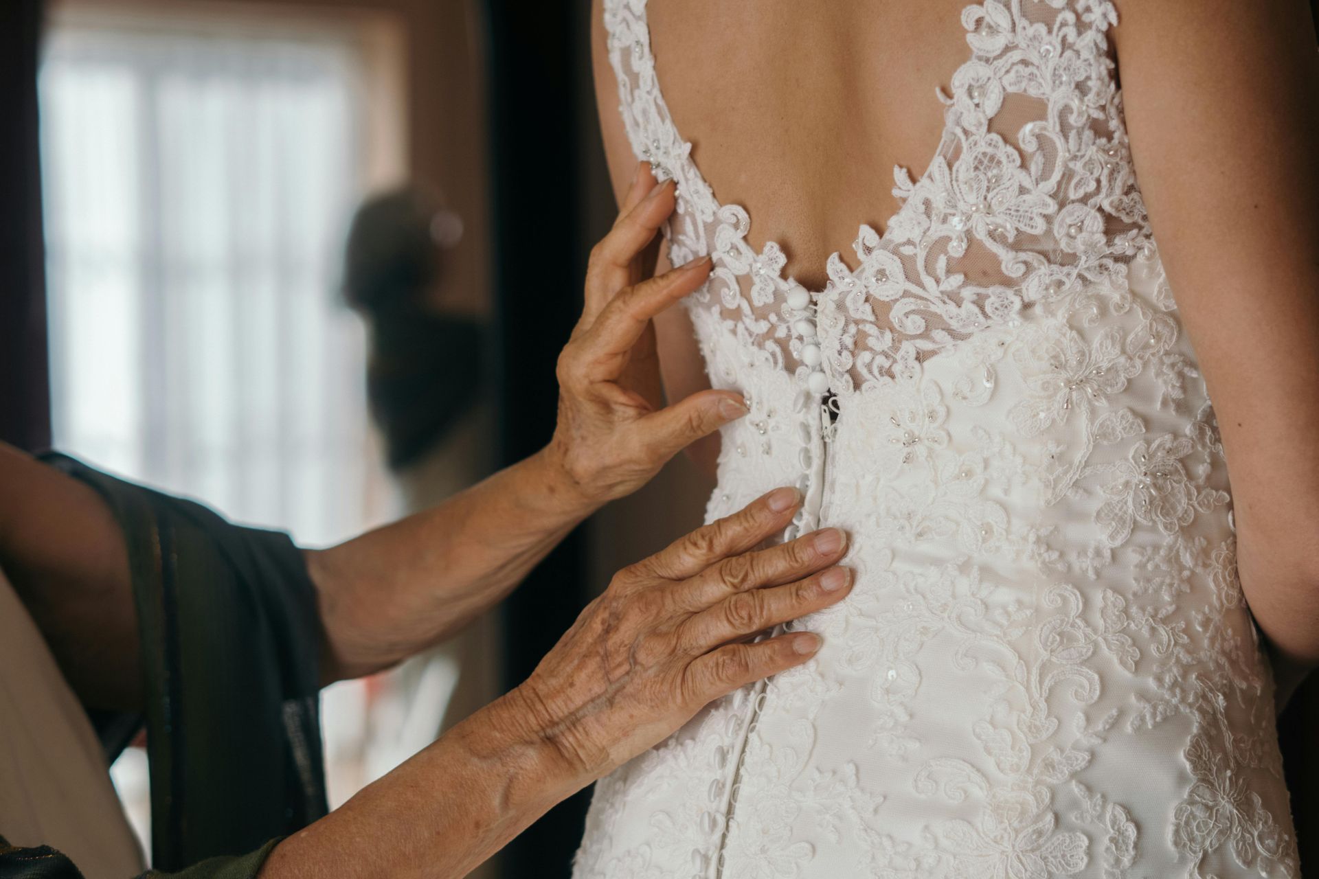 A woman is helping a bride with her wedding dress.