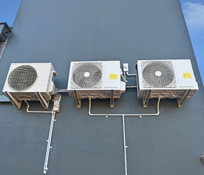 Three air conditioners are mounted on the side of a building.