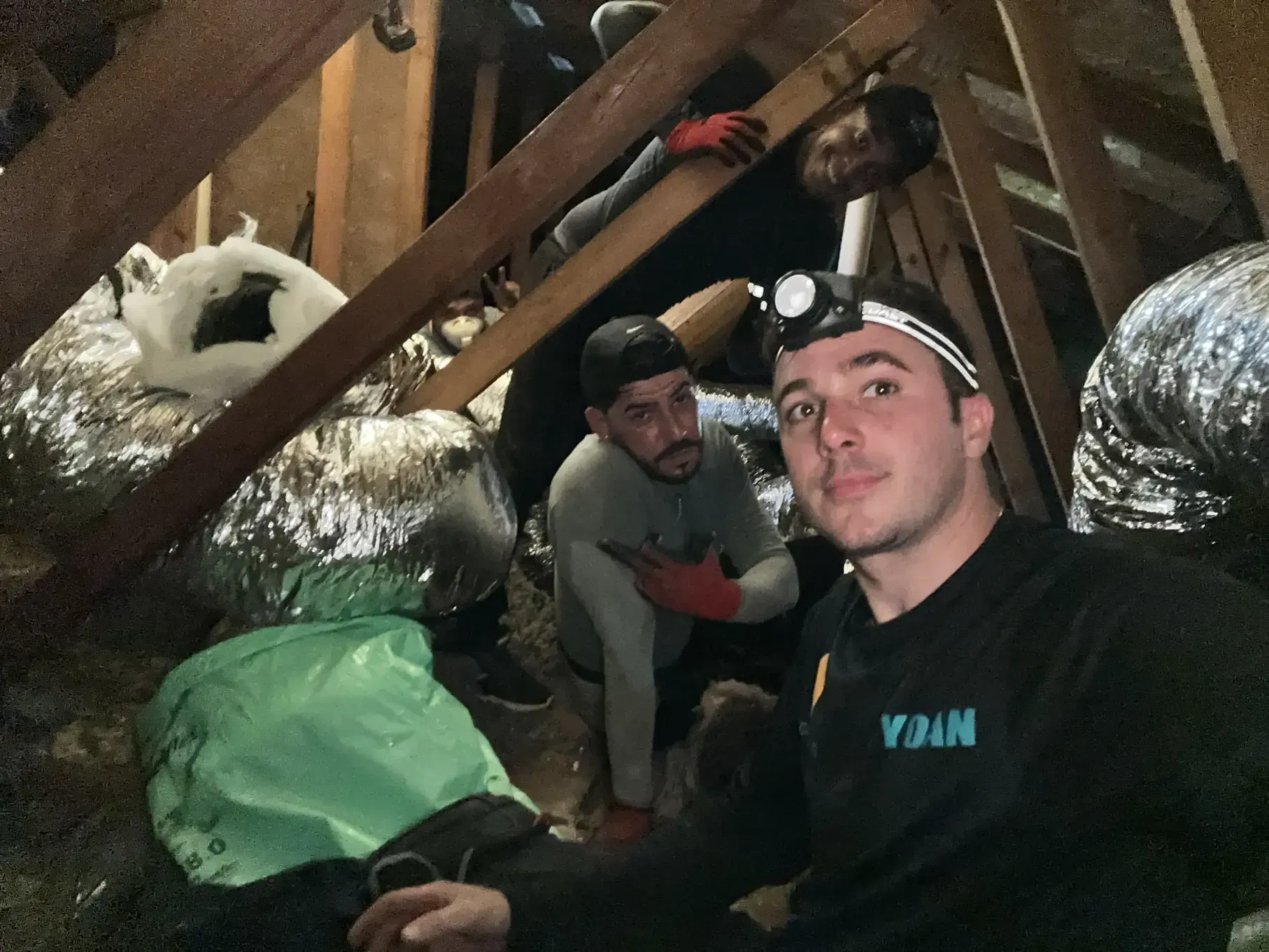 A group of men are working in an attic.