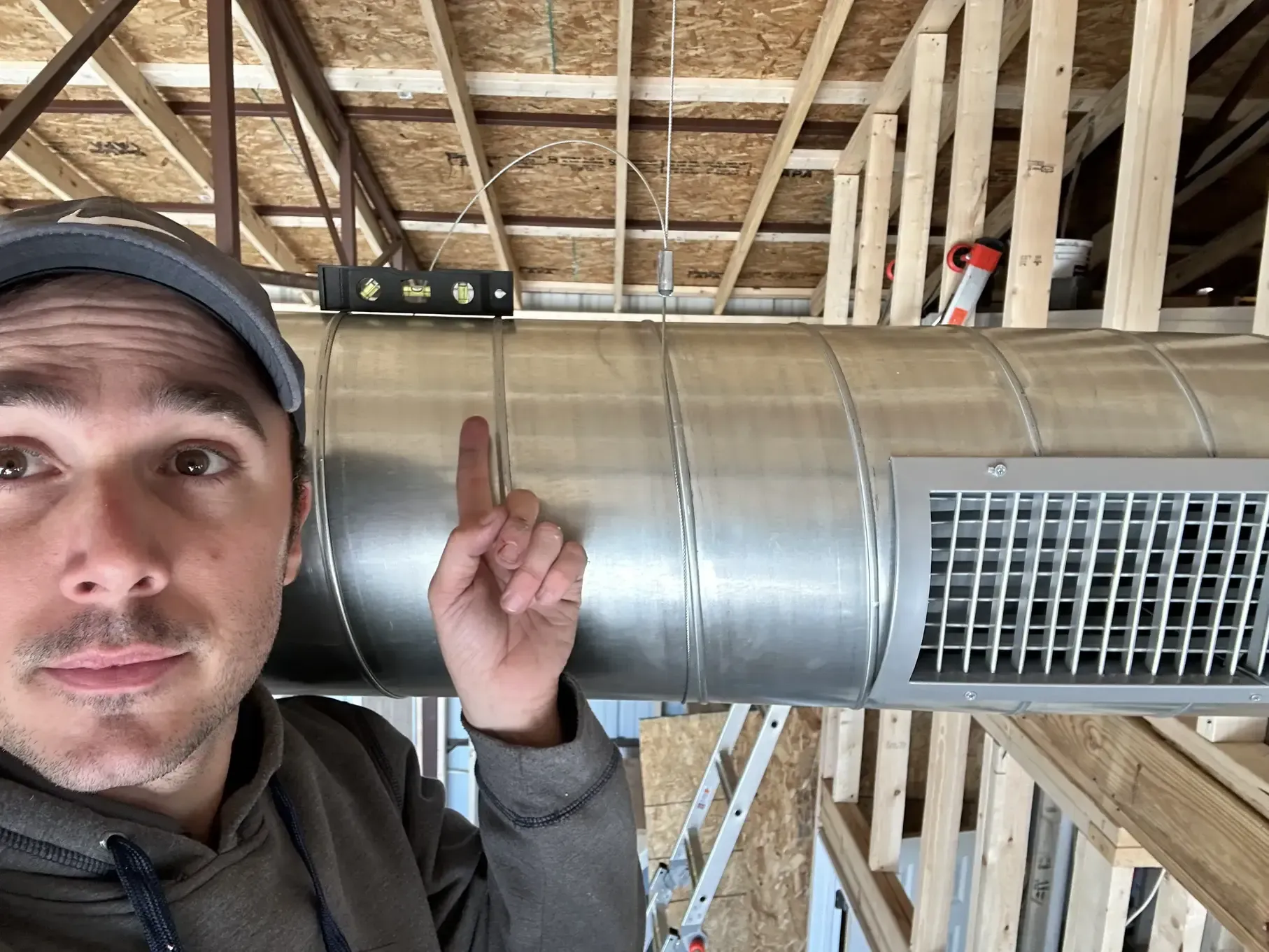 A man is pointing at a metal pipe in a building under construction.