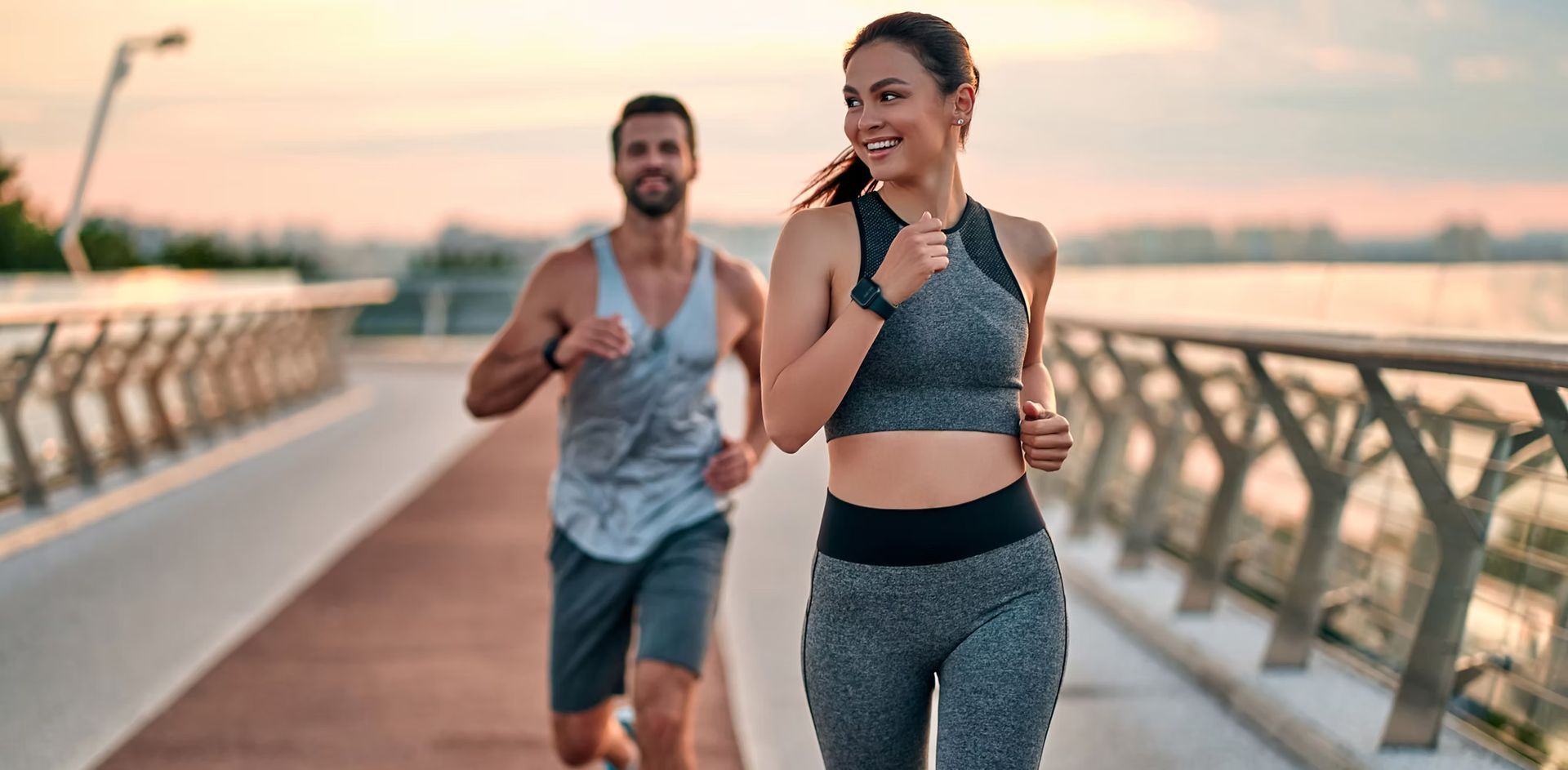 A man and a woman are running on a bridge.