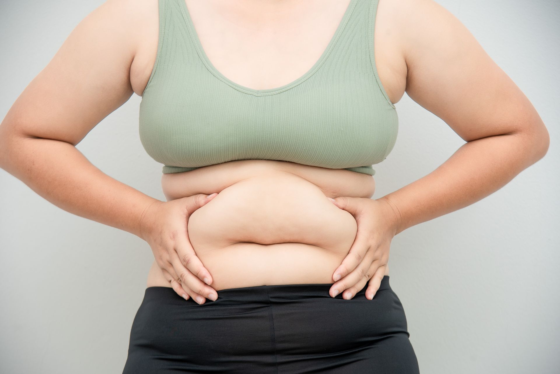 Woman in workout clothes holding her abdomen.