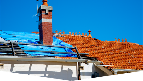 A roof with a chimney and a blue tarp on it.