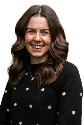A woman wearing a black sweater with white polka dots is smiling.