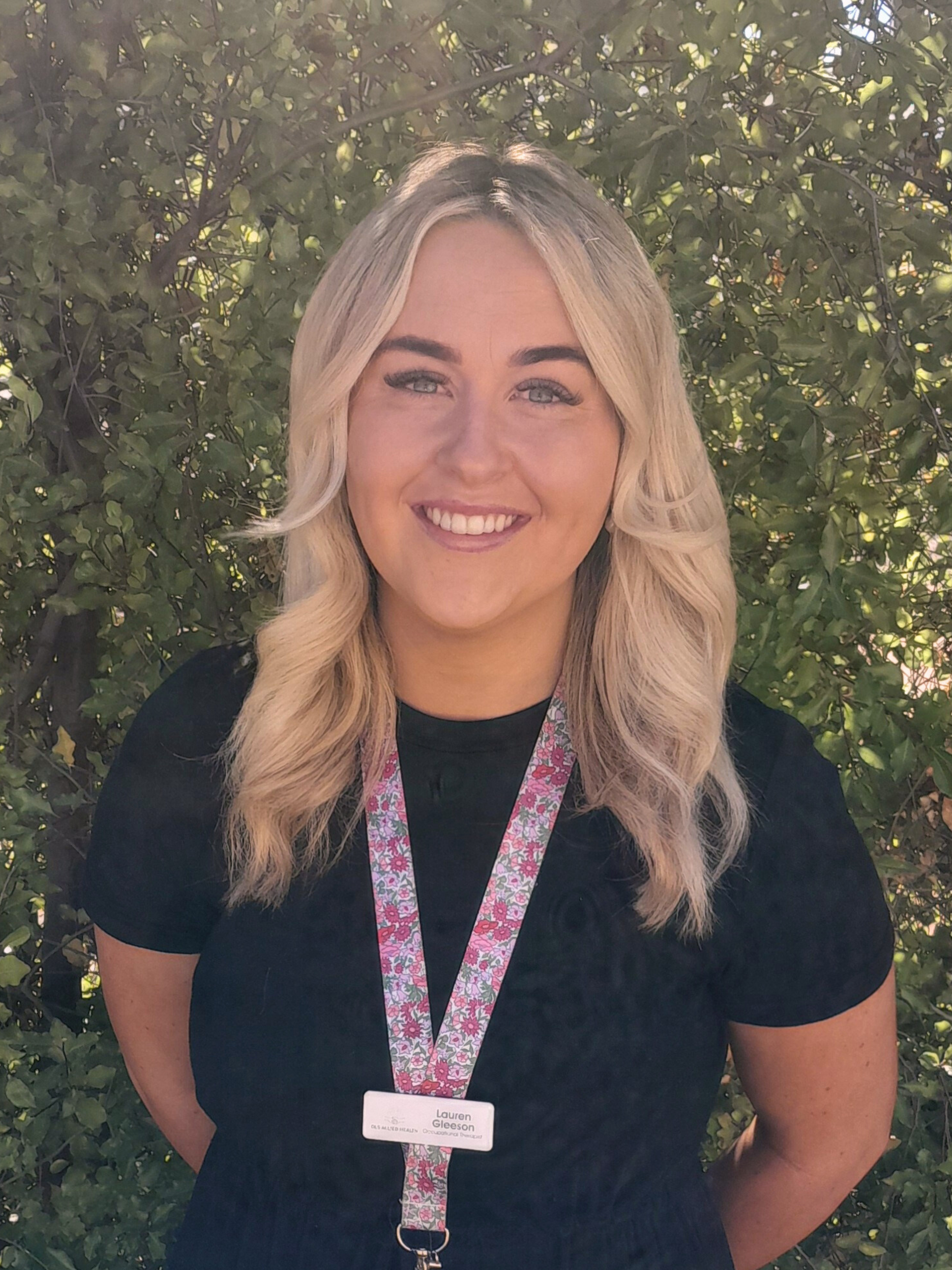 A woman in a pink dress is standing in front of a tree.
