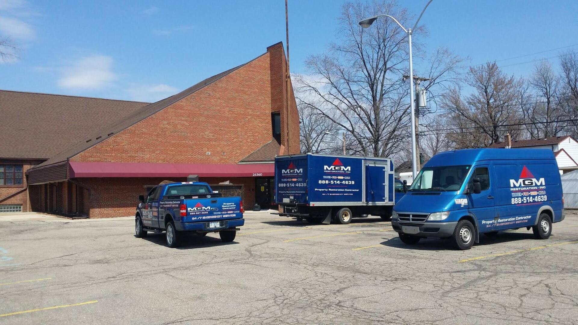 Two blue vans are parked in front of a brick building