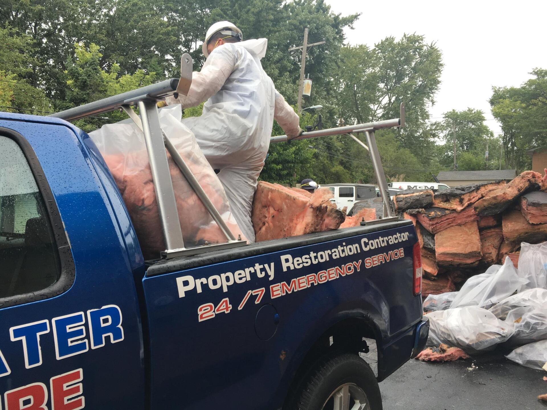 A man is standing on the back of a blue truck.