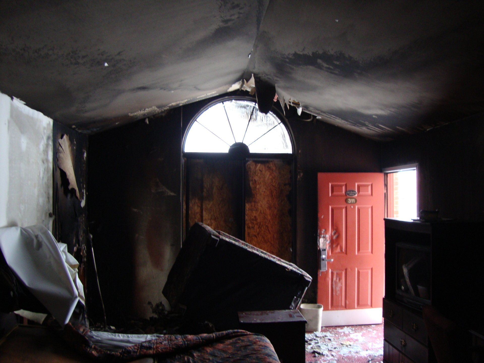 A dark room with a red door and a window