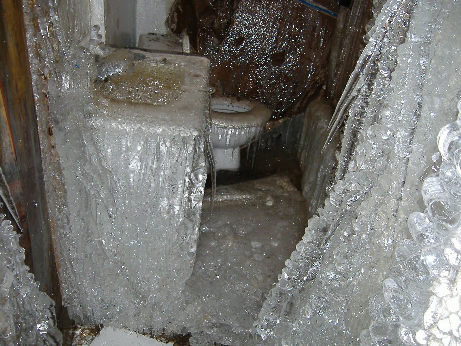A bathroom with a sink and toilet covered in ice.