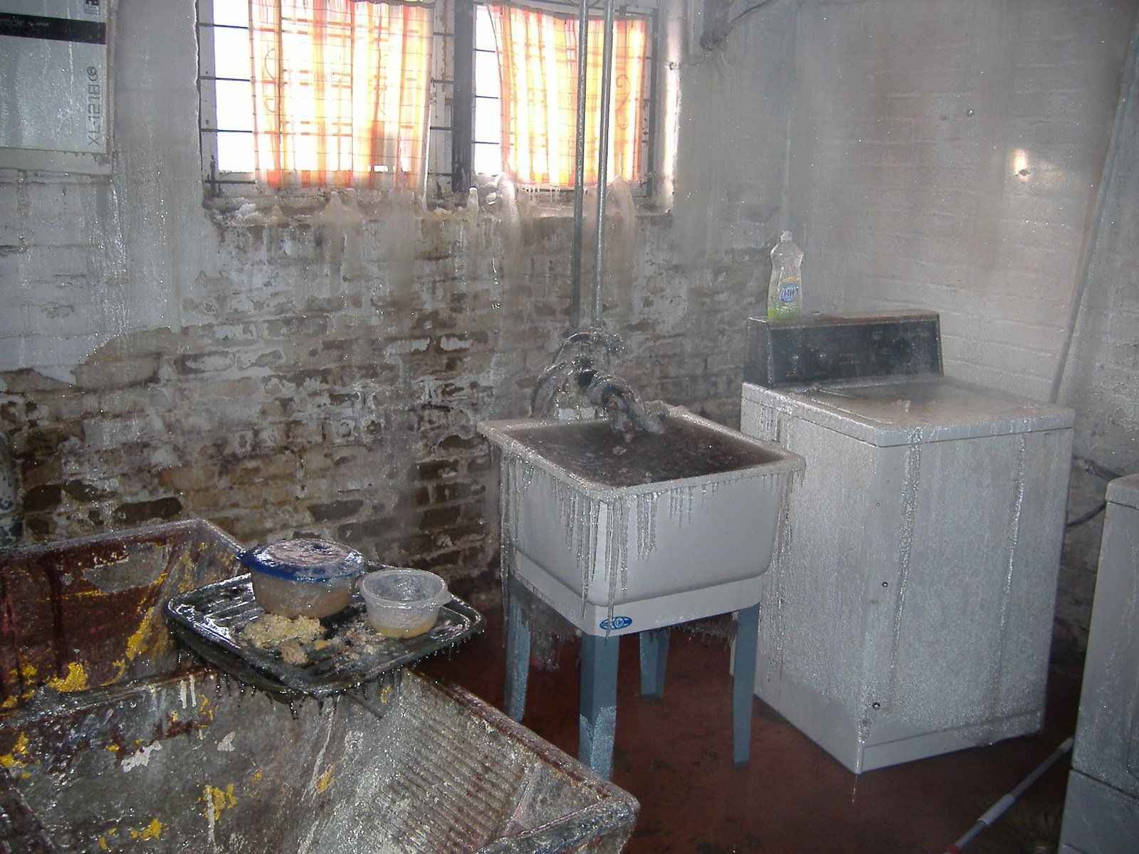 A dirty laundry room with a sink , washer and dryer.