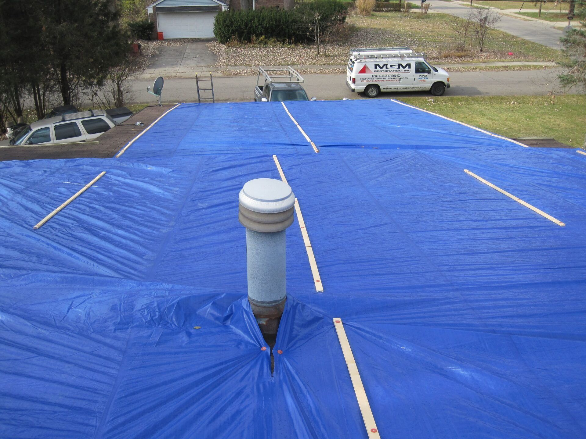 A blue tarp is covering the roof of a house