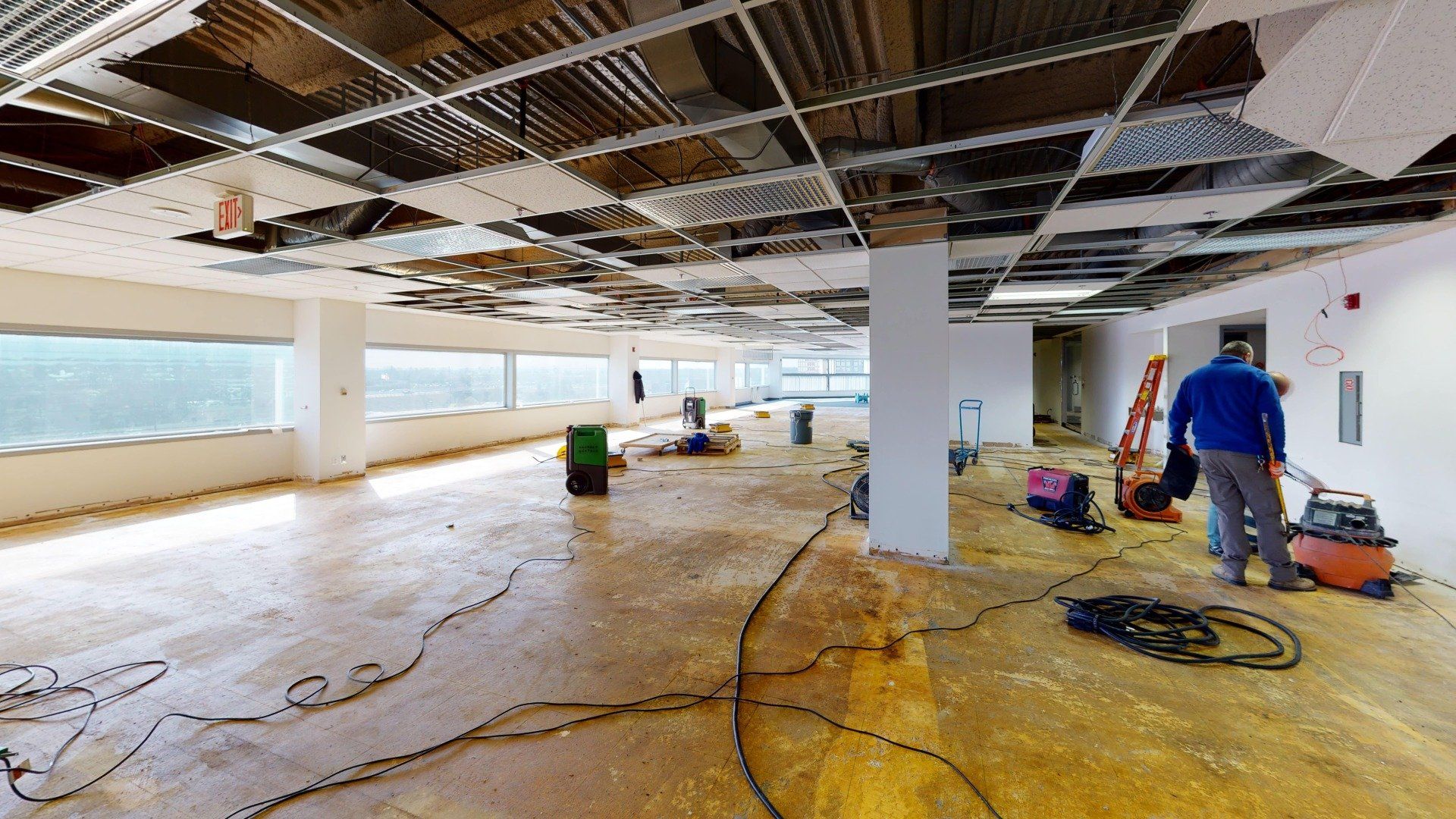A man is standing in an empty room with a vacuum cleaner.