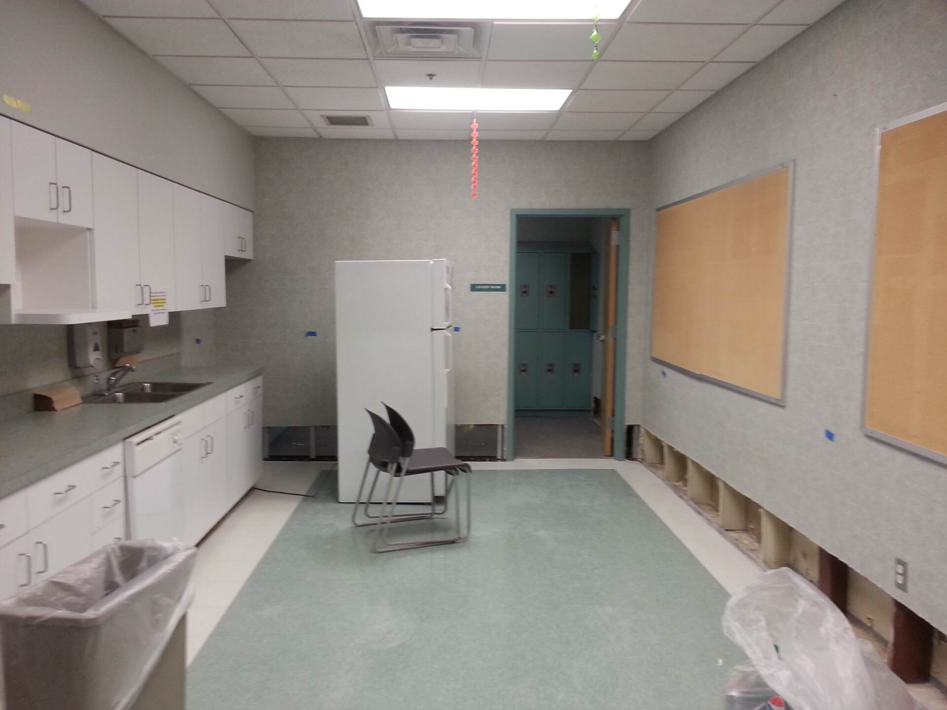An empty kitchen with a refrigerator and chairs