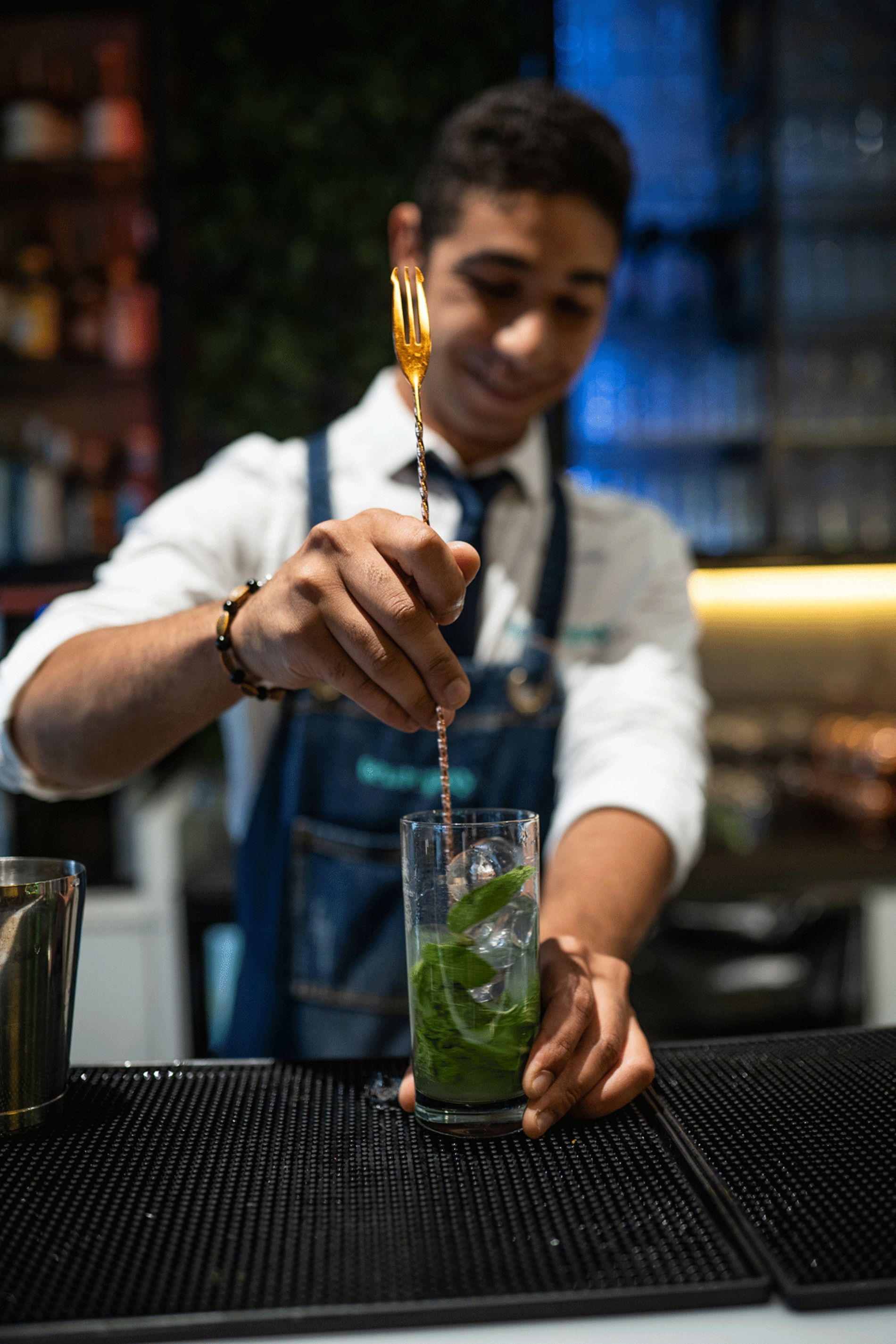 barman che prepara cocktail con foglie di basilico