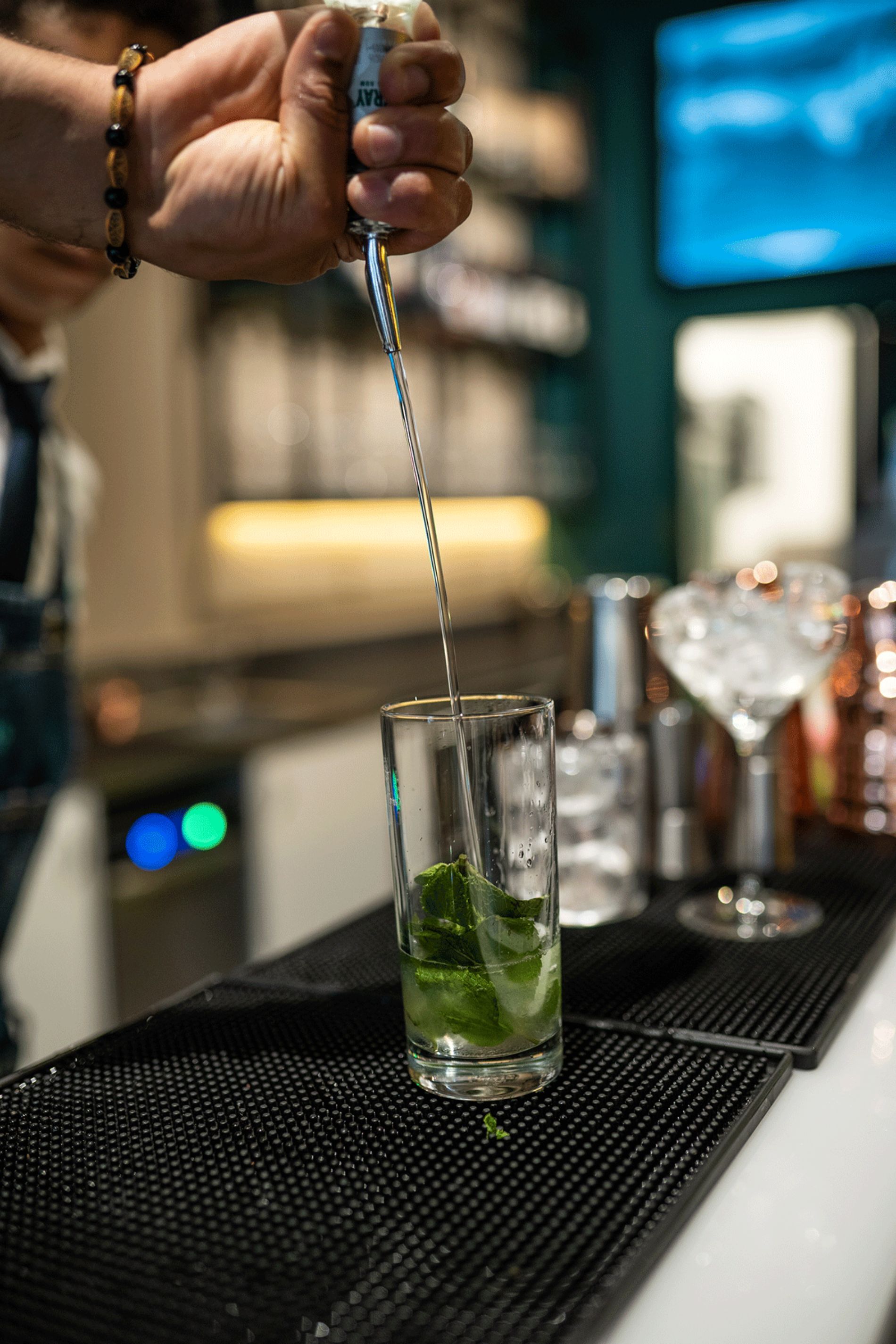 barman che realizza cocktail con foglie di basilico