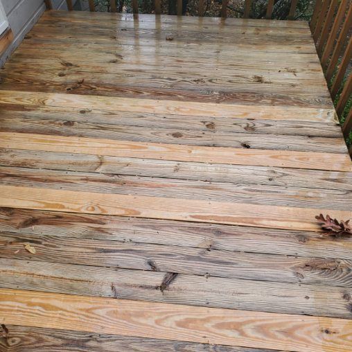 Wooden deck planks, wet from rain. Some are weathered grey, others light brown. Wooden railing visible.
