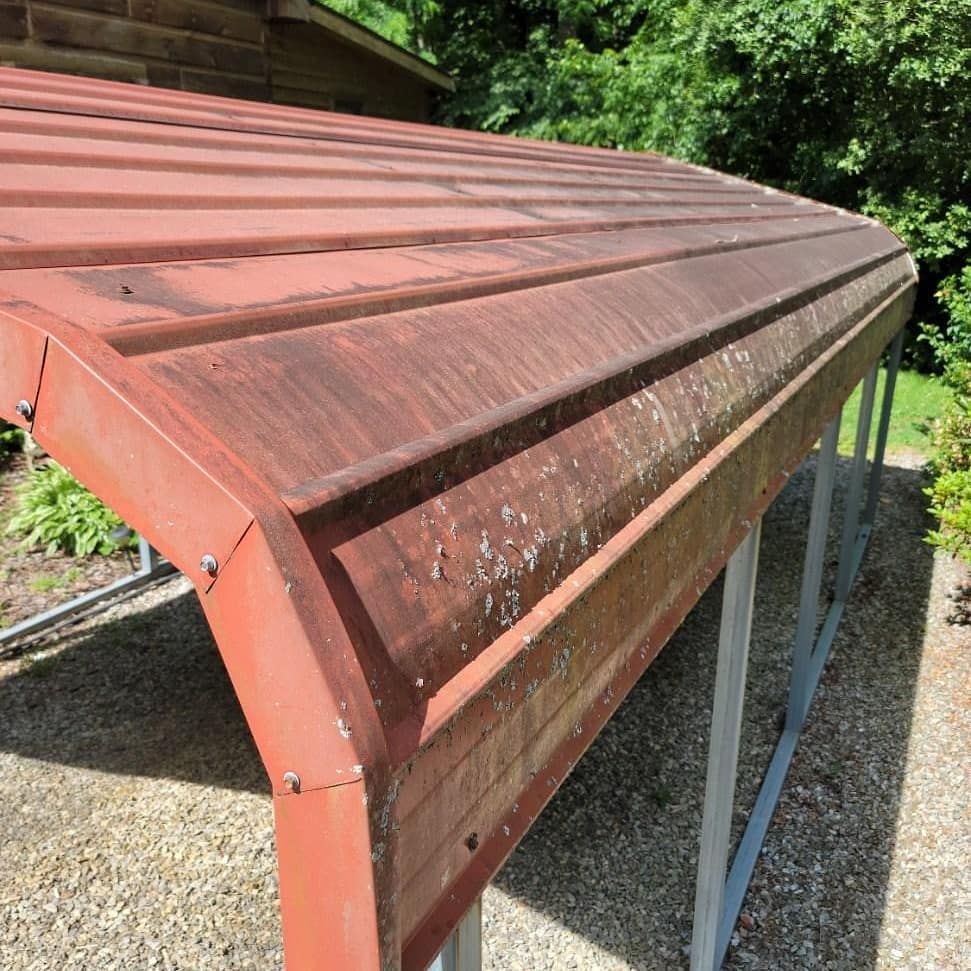 Red metal carport roof with curved edges and signs of wear.