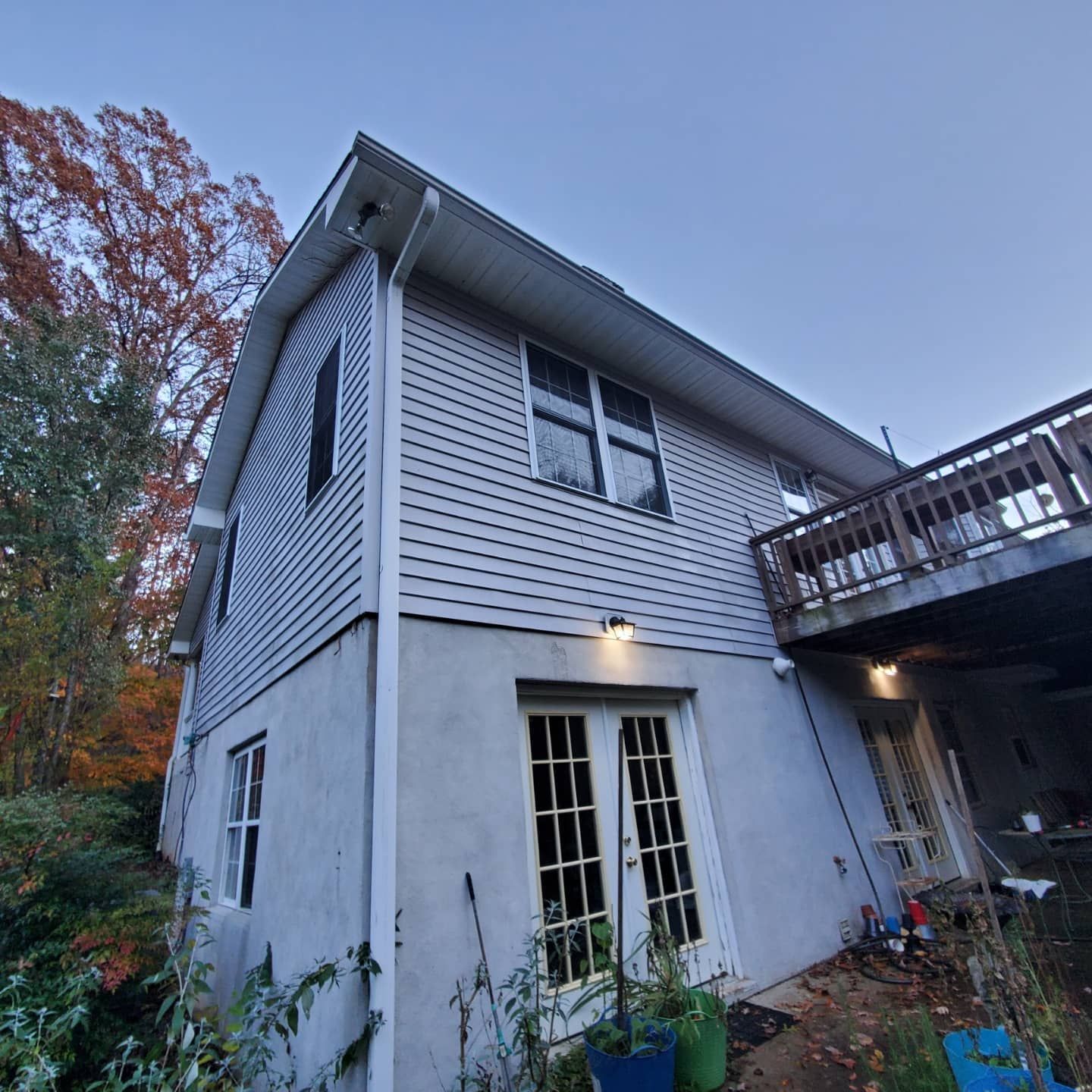 Two-story house with gray siding, white trim, and a wooden deck. French doors are on the lower level.