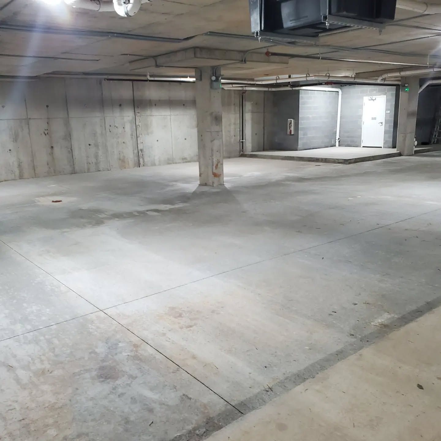 Concrete parking garage with pillars, walls, and a door in the distance.
