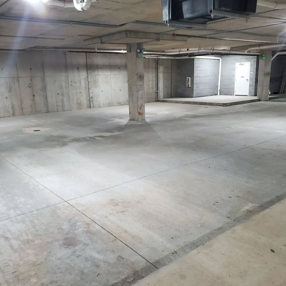 Concrete parking garage with pillars, walls, and a door in the distance.