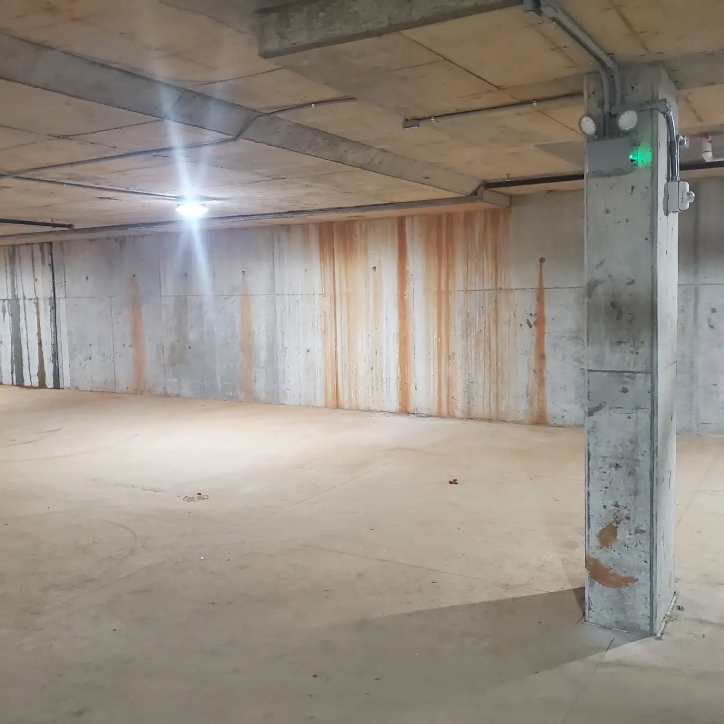 Concrete parking garage with stained walls and a support pillar.