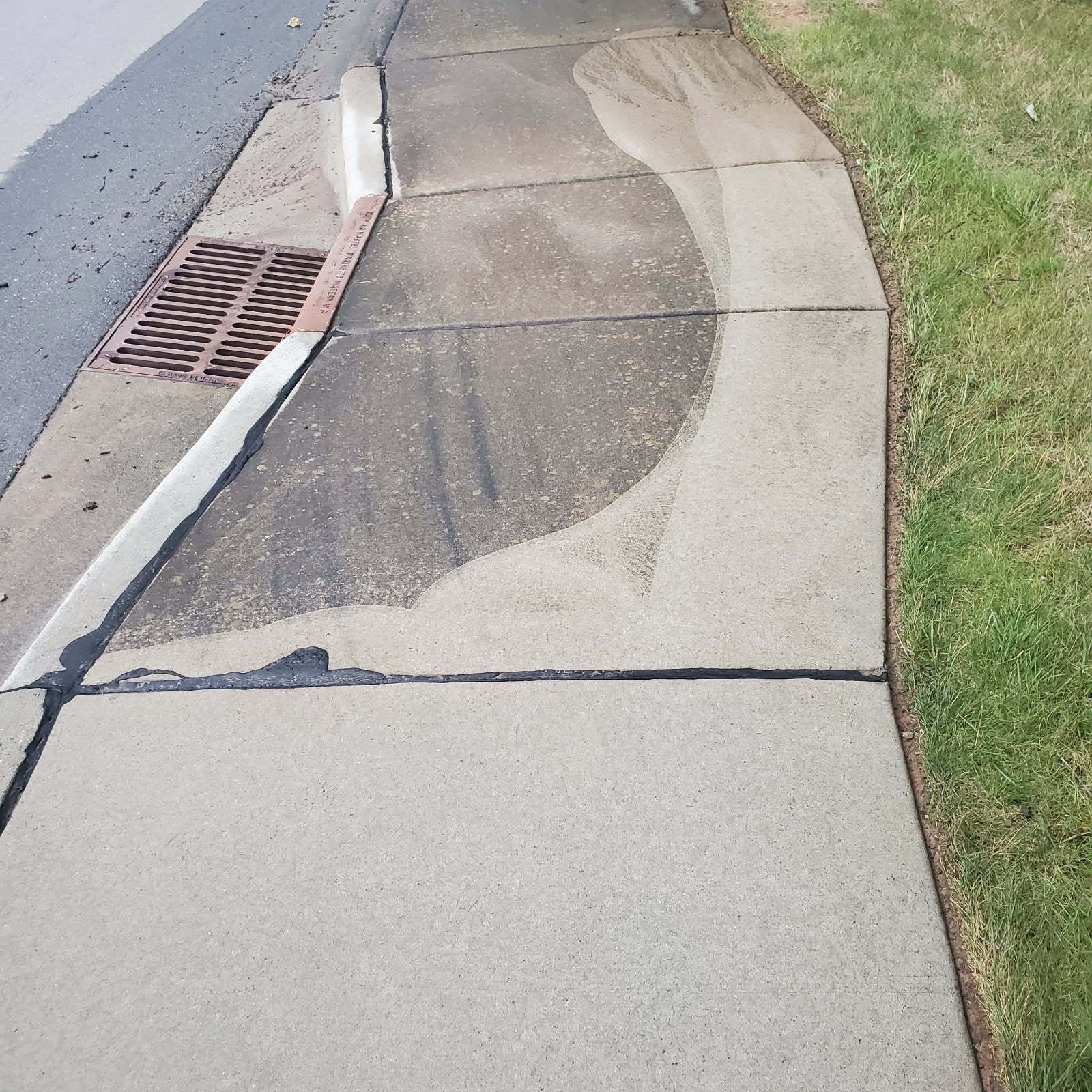 Sidewalk with a portion cleaned, showing contrast between dirty and clean concrete.