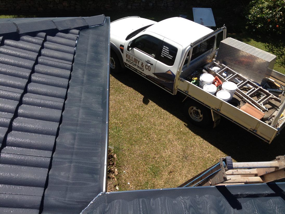 A White Truck is Parked on the Side of a Roof — Killiby & Co Roofing Pty Ltd In Tweed, NSW