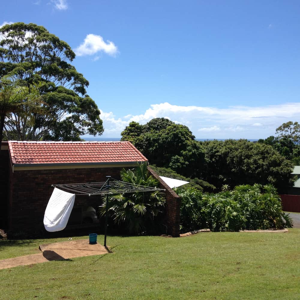 A Brick Building With a Red Tile Roof and a Clothes Line in Front of It — Killiby & Co Roofing Pty Ltd In Tweed, NSW
