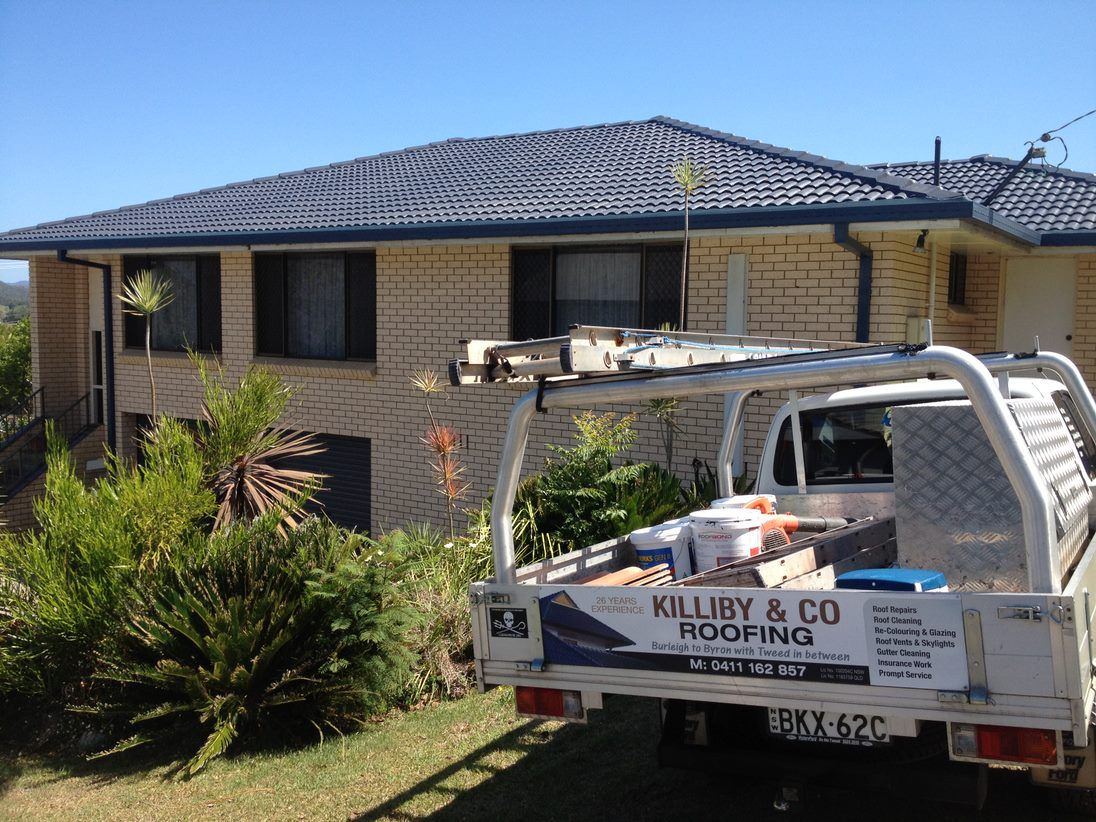 A White Truck is Parked in Front of a Brick House — Killiby & Co Roofing Pty Ltd In Tweed, NSW