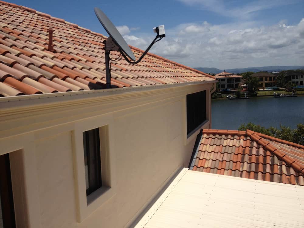 A Satellite Dish on the Roof of a House Overlooking a Body of Water — Killiby & Co Roofing Pty Ltd In Tweed, NSW