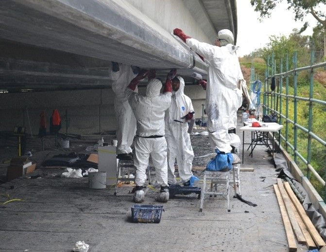 A group of people in white suits are working on a bridge.
