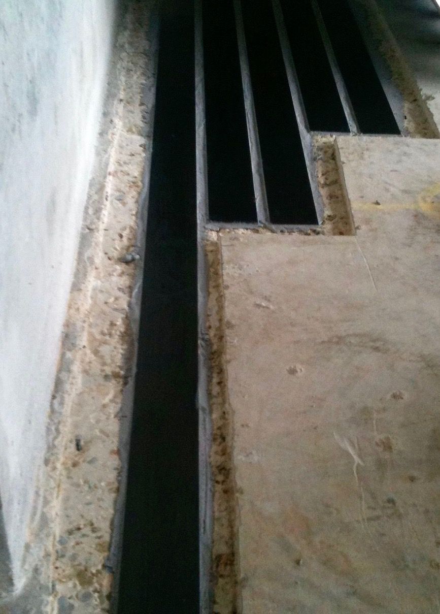 A close up of a metal grate on a concrete floor.