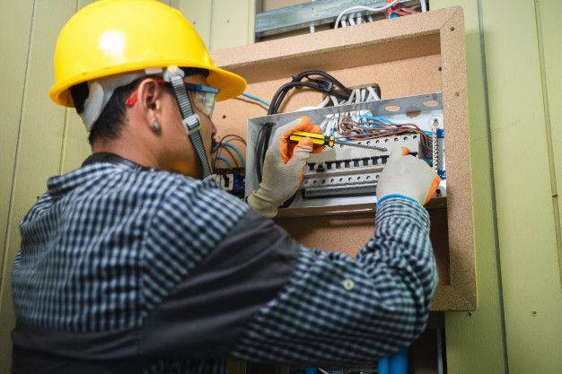 Un electricista está trabajando en una caja eléctrica.