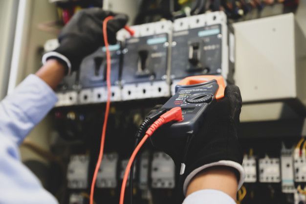 Un electricista está trabajando en una caja eléctrica con un multímetro.