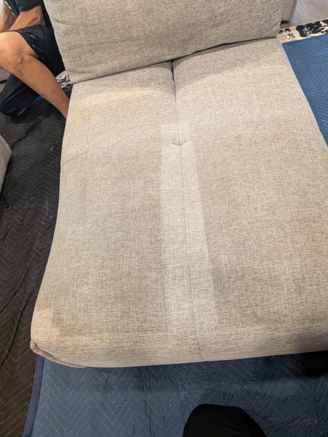 Sofa cushion being cleaned, showing a strip of clean fabric contrasted with the dirty areas.