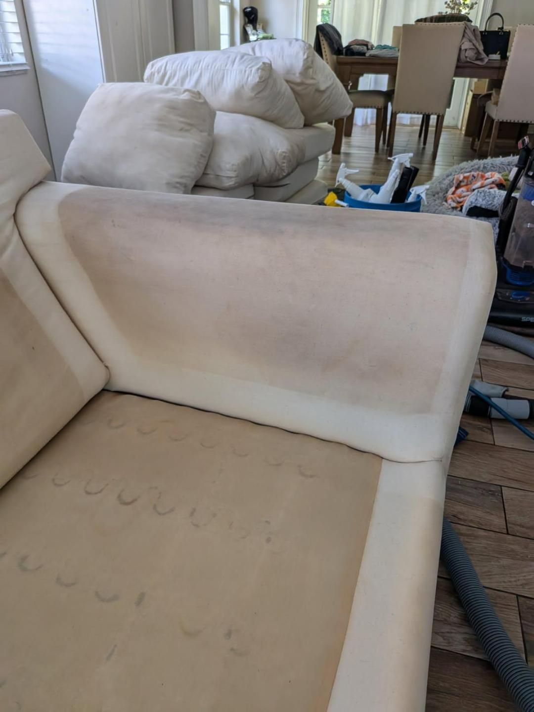 Cream-colored sofa with visible stains, armrest in focus, in a well-lit room.