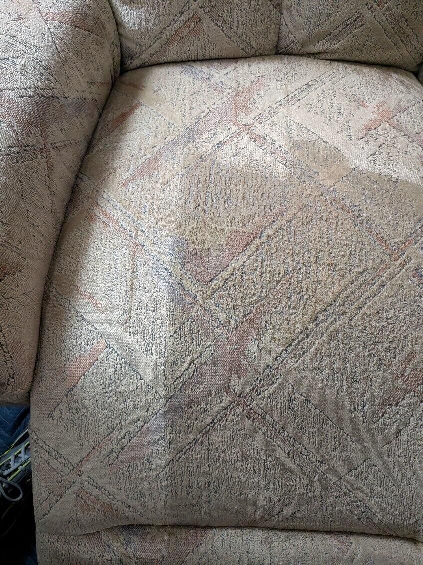 Close-up of a beige armchair with a patterned design.