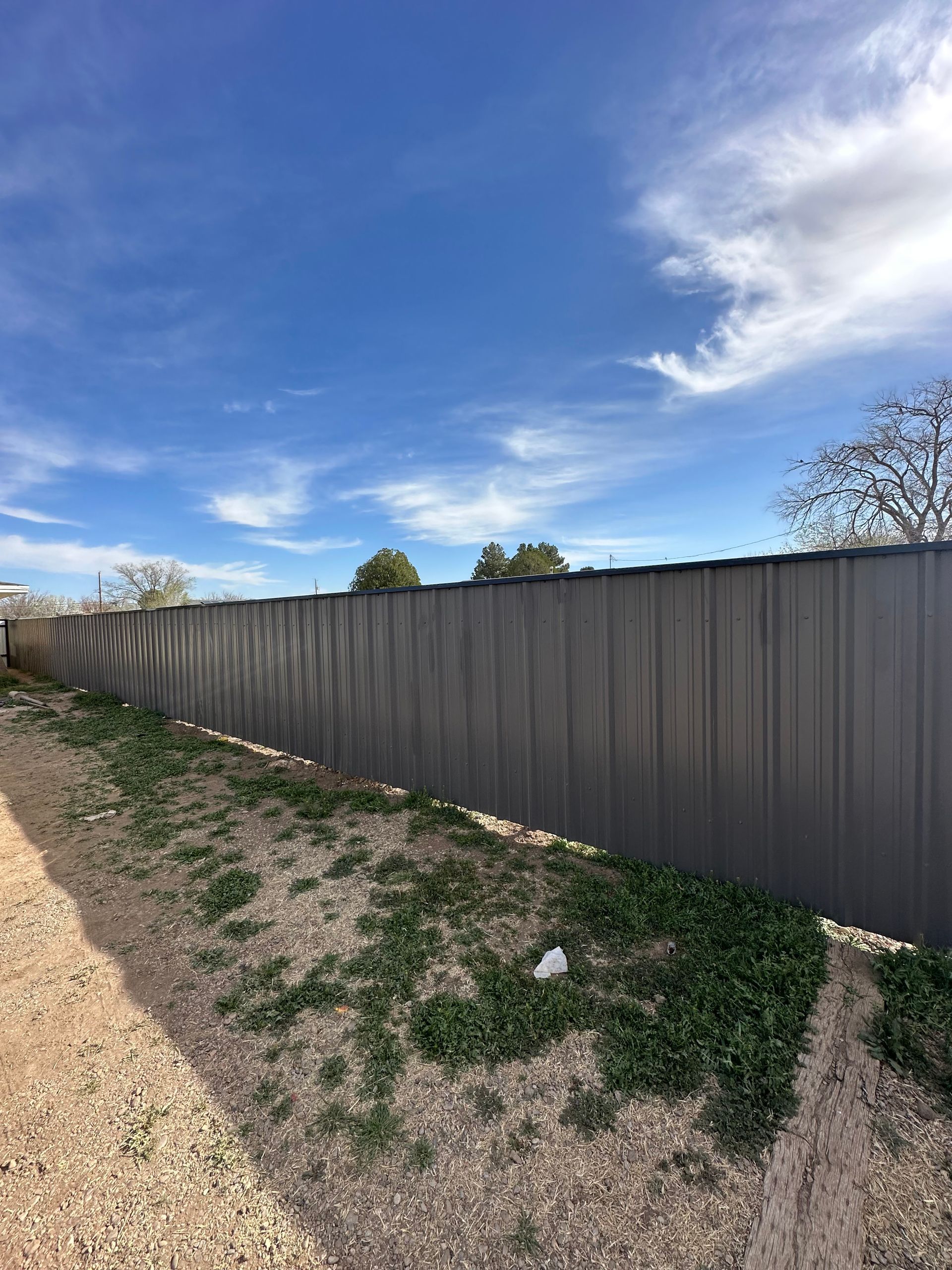 White picket fence surrounding a small, green lawn with a sidewalk on one side.