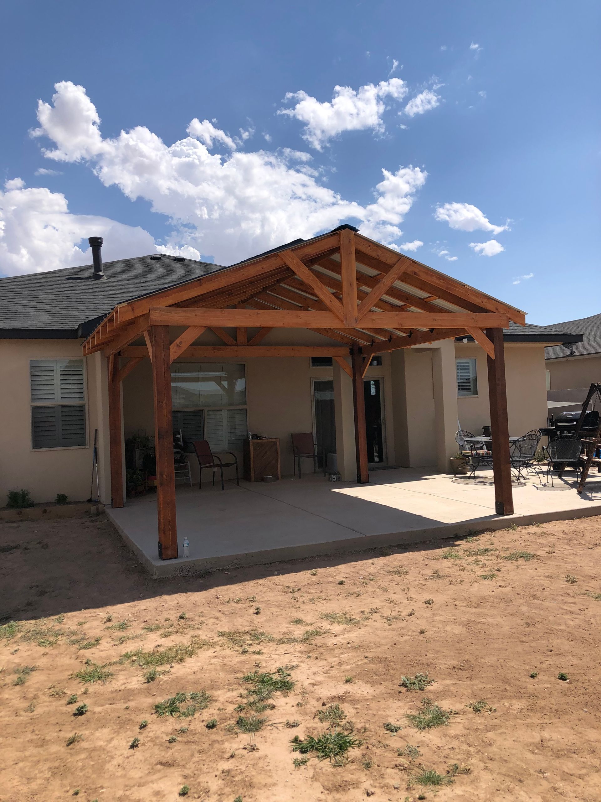 View of a historic town through a wooden porch. Buildings and hills under a blue sky with clouds.