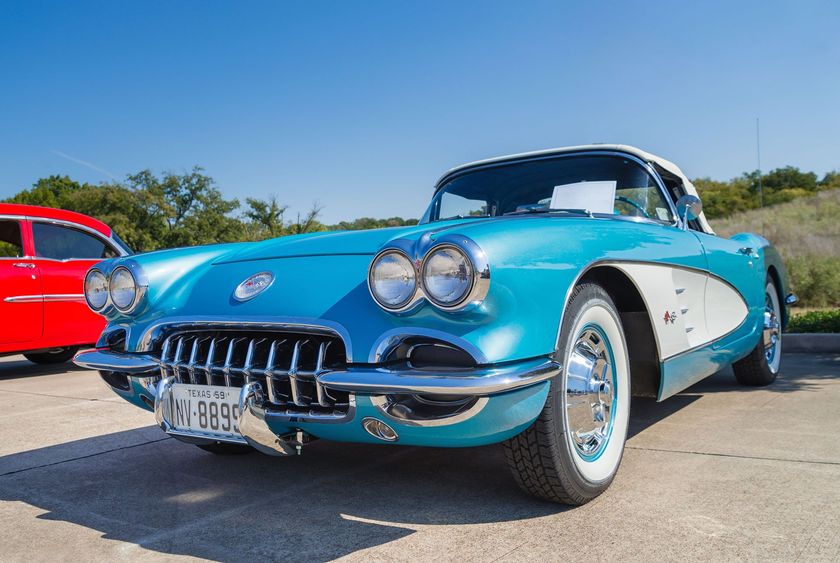 Blue and white vintage Corvette convertible on display, sunny day.